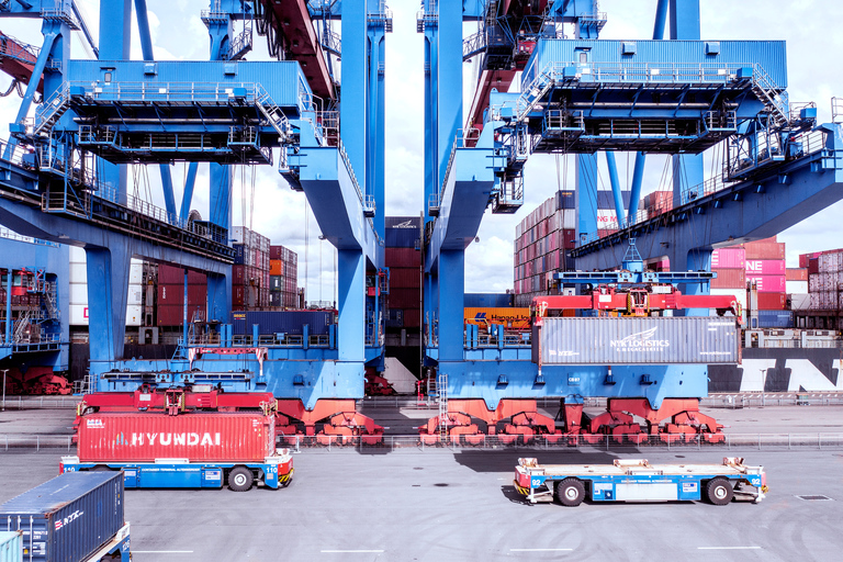 Containerterminal mit Containerbrücken, Containern und automatisierten Transportfahrzeugen im Hafen.